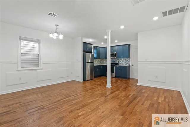 an empty room with wooden floor and kitchen