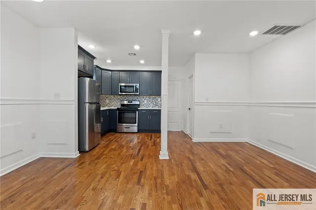 a view of kitchen with cabinets stainless steel appliances and wooden floor