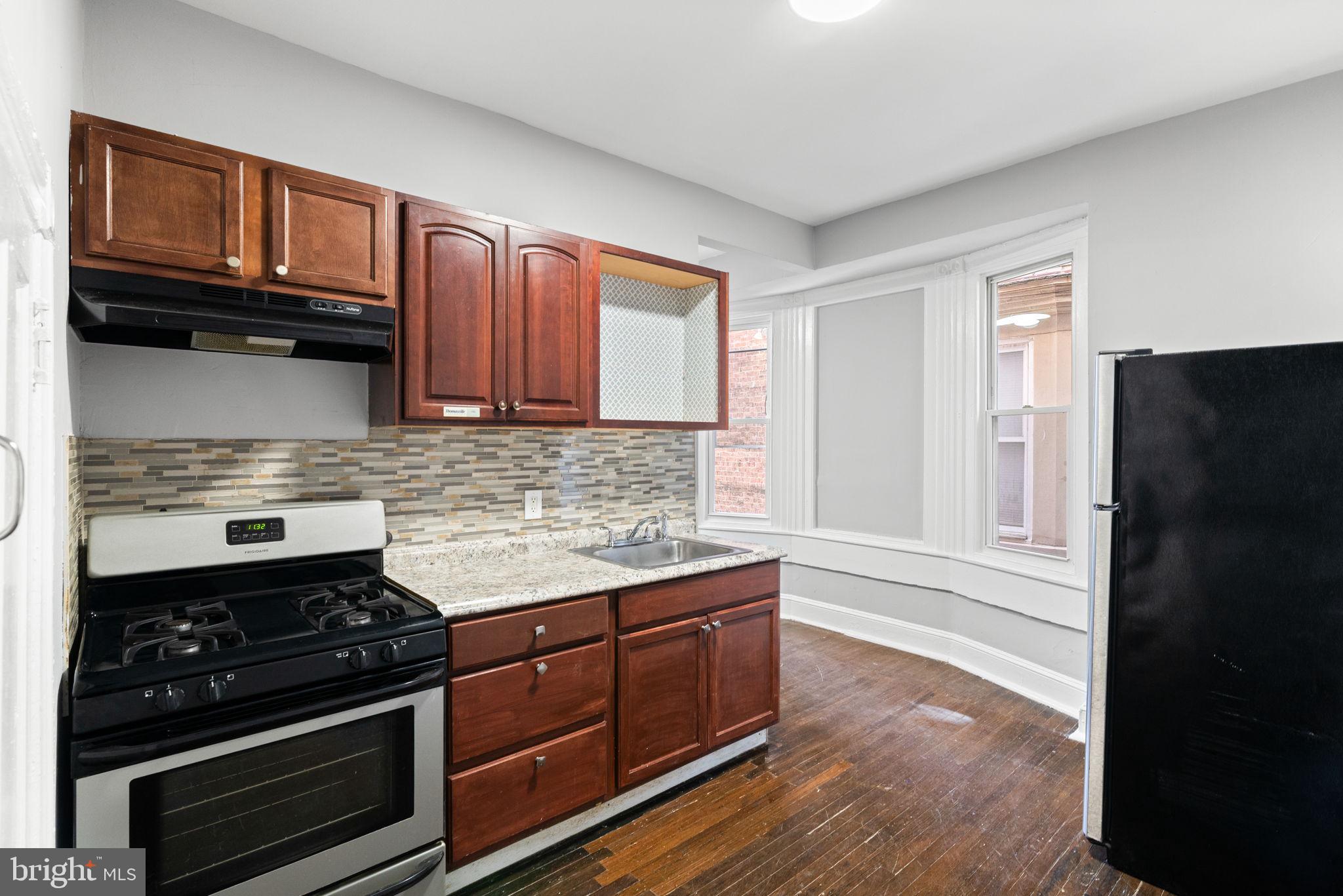 147 Manheim Street Philadelphia, PA 19144 - Photo 6 of 37 a kitchen with granite countertop wooden cabinets and a stove top oven