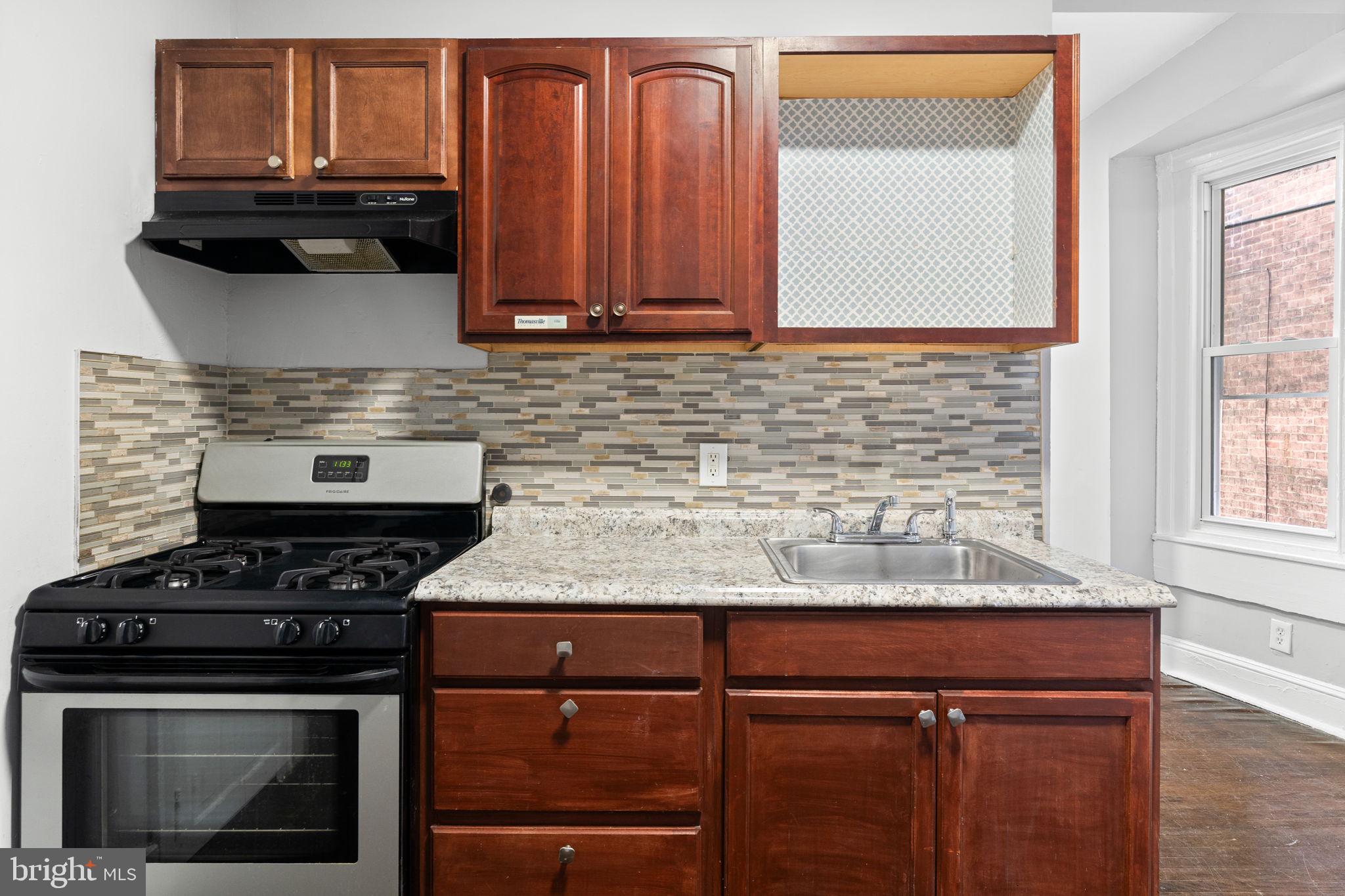 147 Manheim Street Philadelphia, PA 19144 - Photo 7 of 37 a kitchen with granite countertop a stove top oven cabinetry a sink and a window