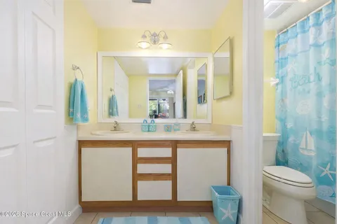 a bathroom with a granite countertop sink a toilet a mirror and shower curtain