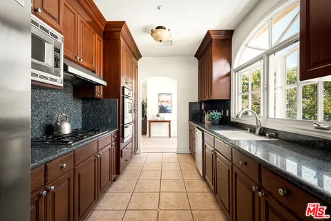 a large kitchen with stainless steel appliances granite countertop a sink and a counter space