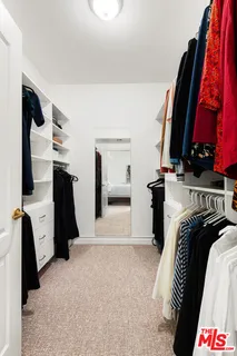 a view of walk in closet with clothes and shoes