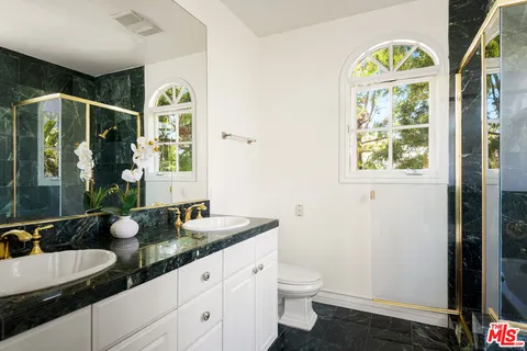 a bathroom with double vanity a toilet a and a window
