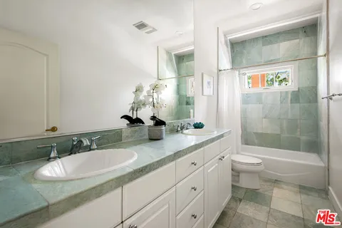 a bathroom with a double vanity sink toilet and shower