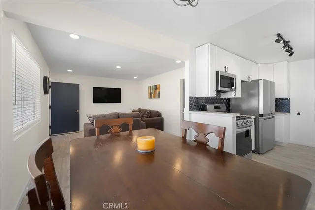 a living room with stainless steel appliances furniture a flat screen tv and a kitchen view