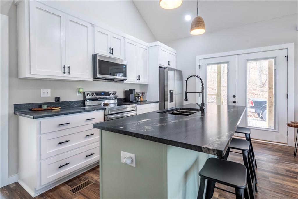 110 Burnt Mountain Cove Road Jasper, GA 30143 - Photo 19 of 33 a kitchen with white cabinets stainless steel appliances and dining table