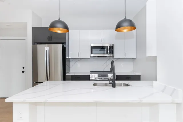 a kitchen with stainless steel appliances granite countertop a sink a stove and a refrigerator with wooden floor