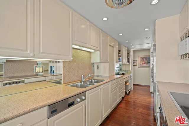 a large white kitchen with a sink and dishwasher