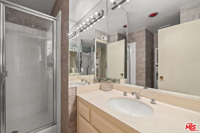 a bathroom with a granite countertop sink mirror and a shower