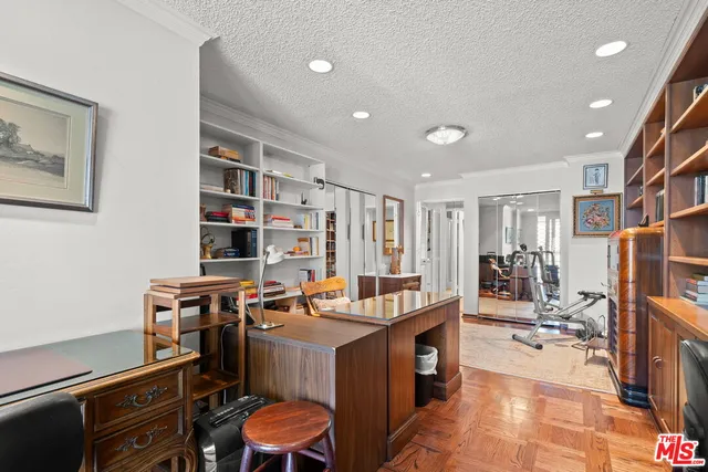 a work room with furniture a bookshelf and a window