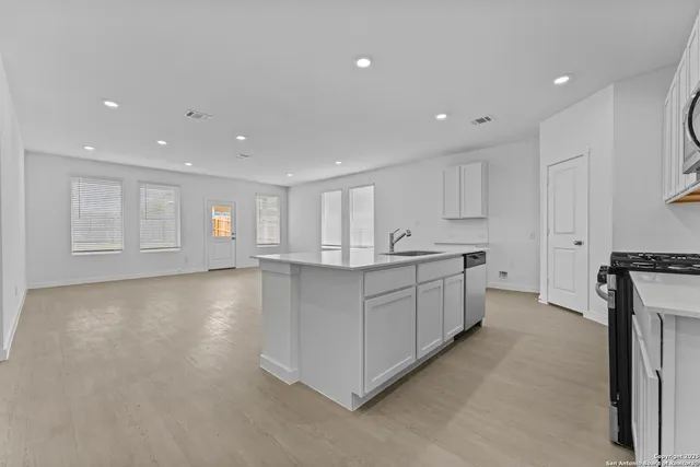 a large white kitchen with center island and a window