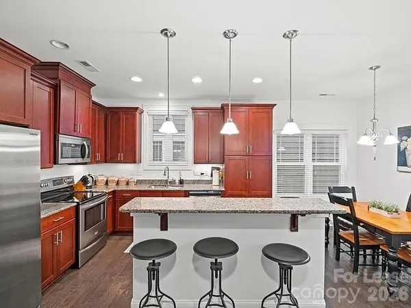 a kitchen with stainless steel appliances granite countertop a sink a stove a refrigerator a kitchen island with chairs and cabinets