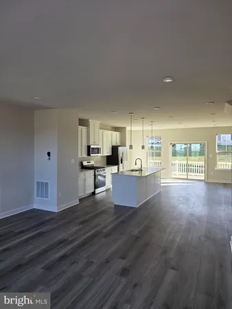 a large living room with kitchen view and wooden floor