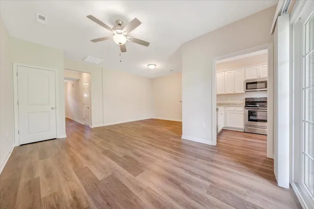 a view of empty room with wooden floor and fan