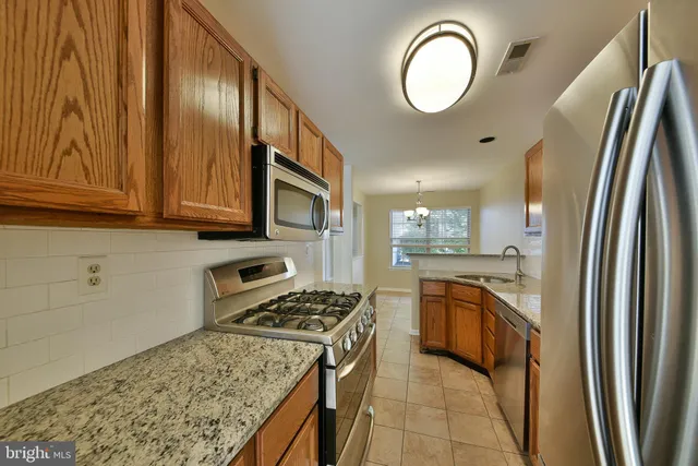 a kitchen with stainless steel appliances granite countertop a stove a sink and a refrigerator