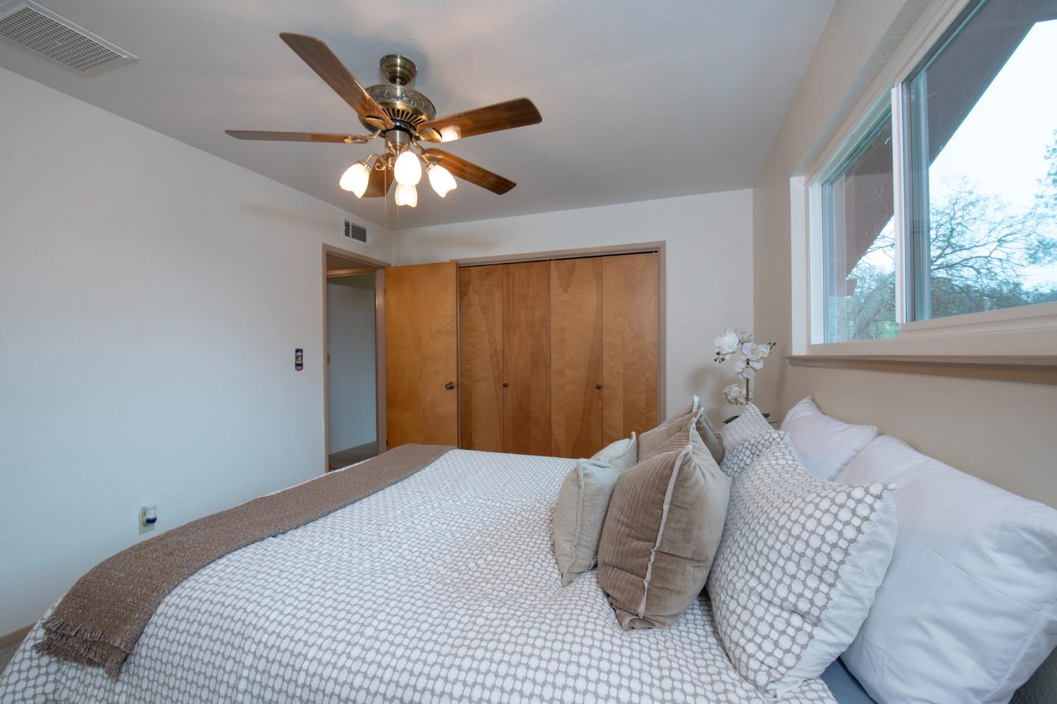 21256 Tollhouse Road Clovis, CA 93619 - Photo 21 of 30 a bedroom with a large bed chandelier and a window