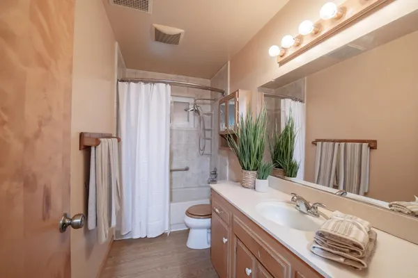 a bathroom with a granite countertop sink a toilet a mirror and shower
