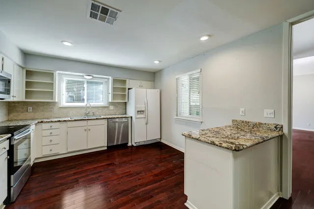 a kitchen with granite countertop a sink cabinets and wooden floor