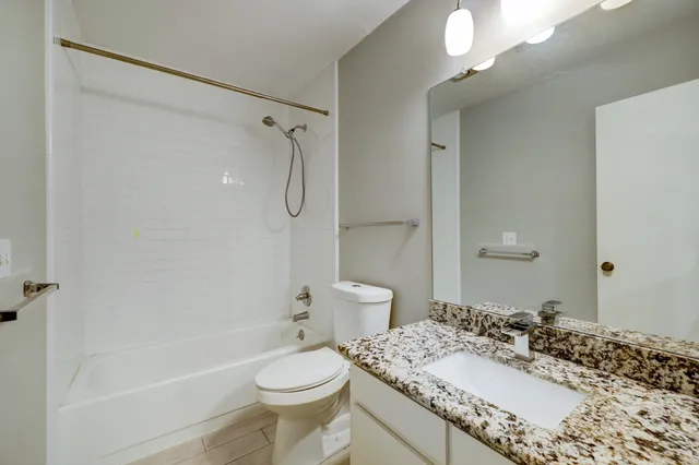 a bathroom with a granite countertop sink toilet mirror and shower