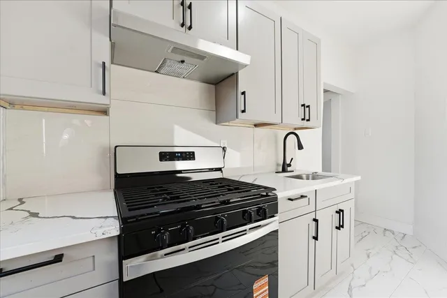 a kitchen with stainless steel appliances granite countertop a stove a sink and white cabinets