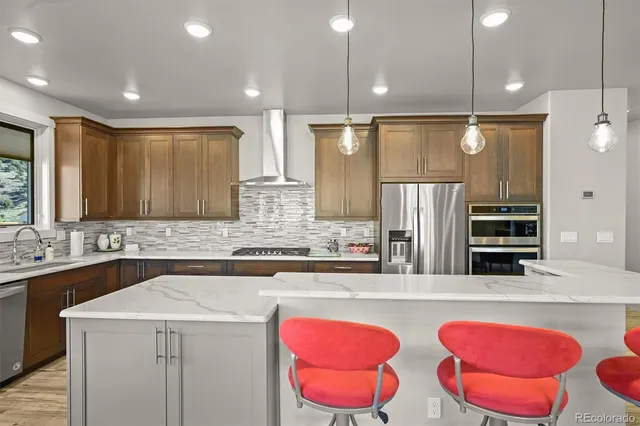 a kitchen with stainless steel appliances kitchen island granite countertop a refrigerator a sink and wooden floor