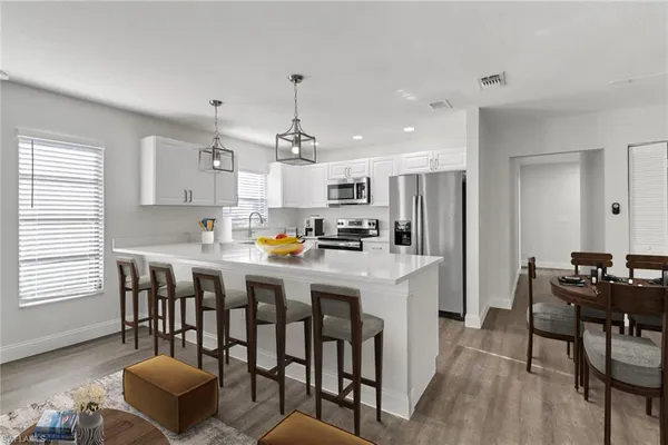 a kitchen with kitchen island granite countertop a dining table chairs stove and refrigerator