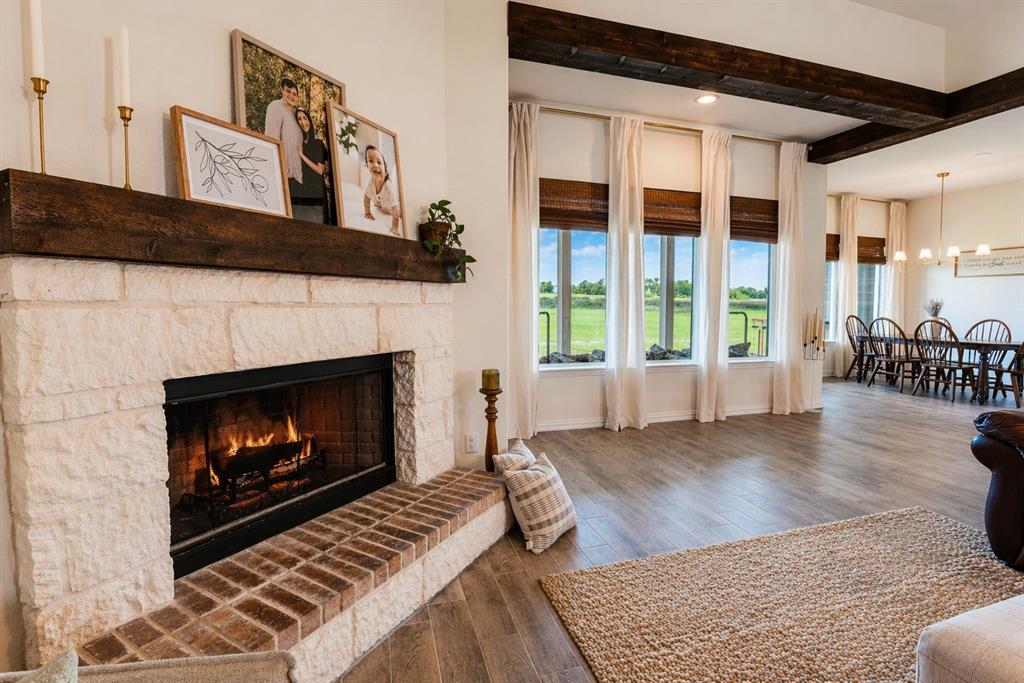 1530 County Road 200 Valley View, TX 76272 - Photo 8 of 34 Stone fireplace with a substantial timber mantel, brick hearth, wood-finish flooring, and exposed ceiling beams