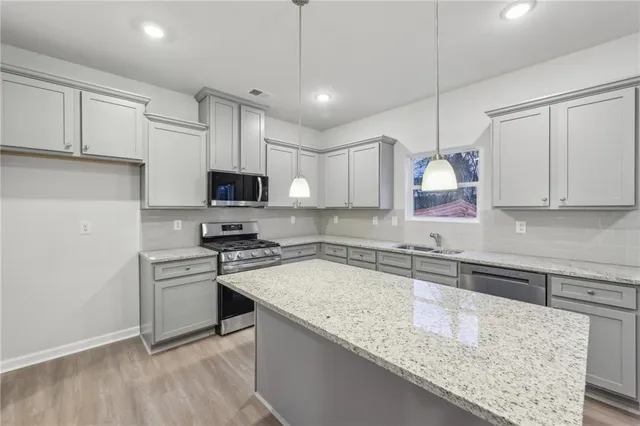 a kitchen with granite countertop a sink stainless steel appliances and white cabinets
