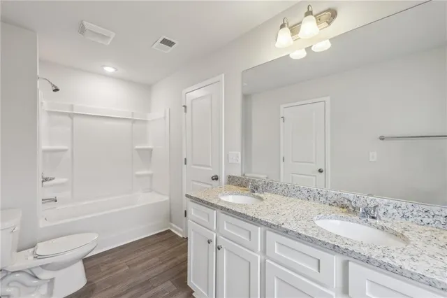 a bathroom with a granite countertop sink a toilet and shower