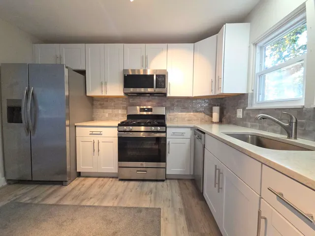 a kitchen with white cabinets and appliances
