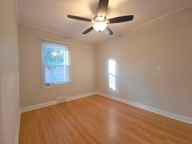 an empty room with windows and fan