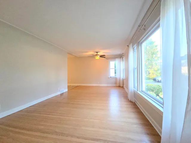 a view of a big room with wooden floor and windows