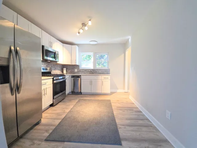 a large kitchen with stainless steel appliances granite countertop a stove a sink and a refrigerator