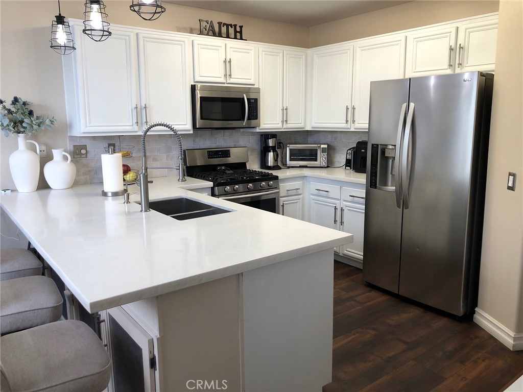 25530 Hemingway Avenue Stevenson Ranch, CA 91381 - Photo 6 of 29 a kitchen with stainless steel appliances a refrigerator microwave stove sink and cabinets