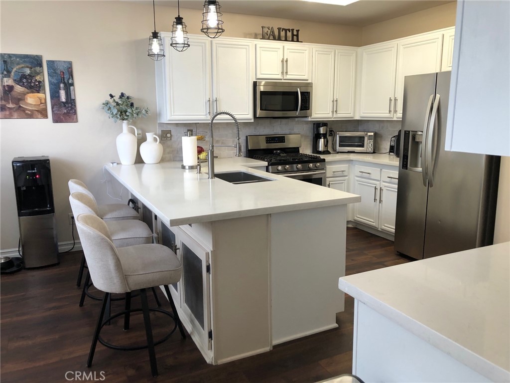 25530 Hemingway Avenue Stevenson Ranch, CA 91381 - Photo 9 of 29 a kitchen with stainless steel appliances a stove a sink a microwave a refrigerator a stove a dining table and chairs