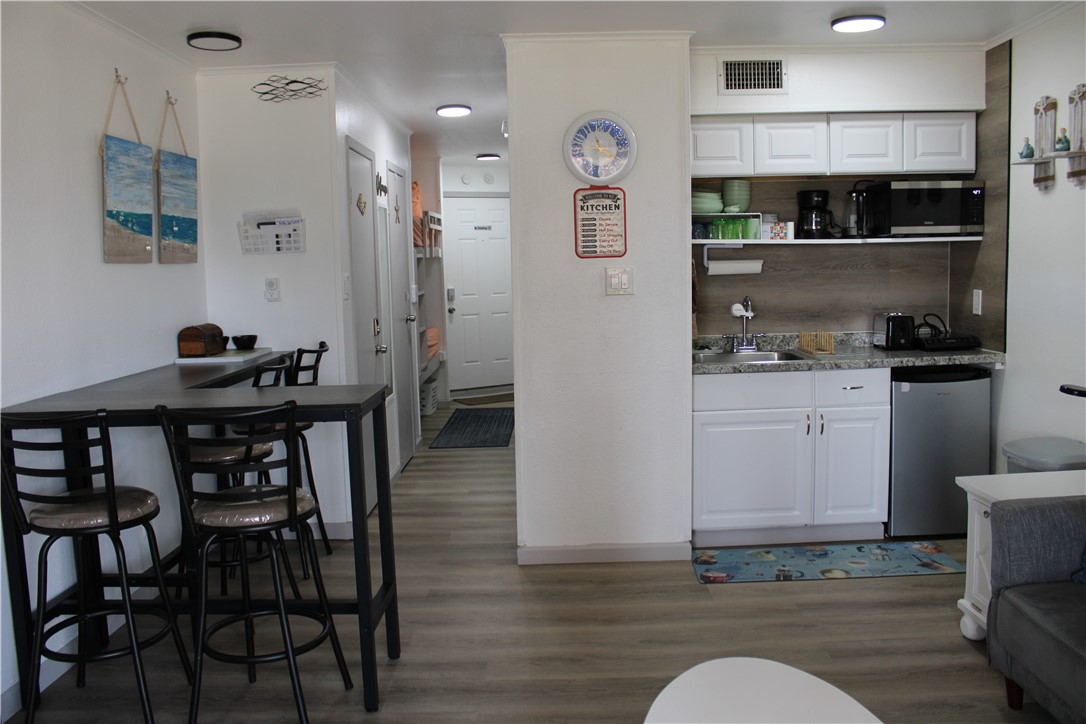 3938 Surfside Boulevard, Unit 3129 Corpus Christi, TX 78402 - Photo 4 of 39 a kitchen with stainless steel appliances granite countertop a table chairs in it and wooden floors