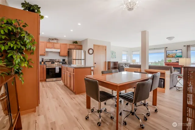 a kitchen with stainless steel appliances a dining table chairs stove and a large window