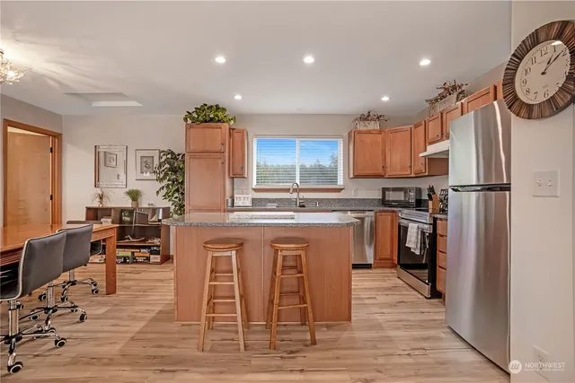 a kitchen with stainless steel appliances granite countertop a table chairs sink refrigerator and cabinets