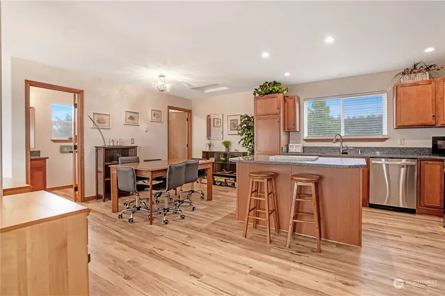 a kitchen with stainless steel appliances granite countertop a stove top oven a sink a dining table and chairs