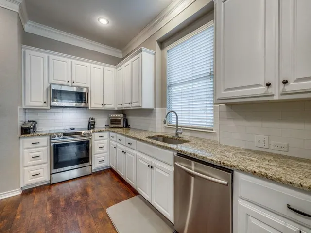 a kitchen with granite countertop cabinets stainless steel appliances and a sink