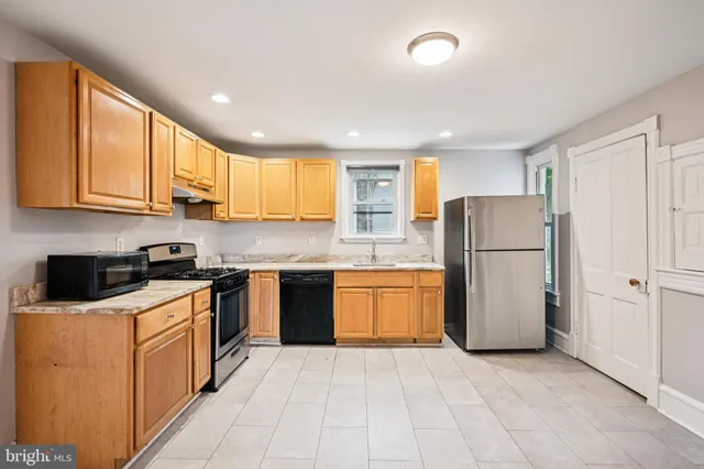 a kitchen with a refrigerator a stove top oven and cabinets