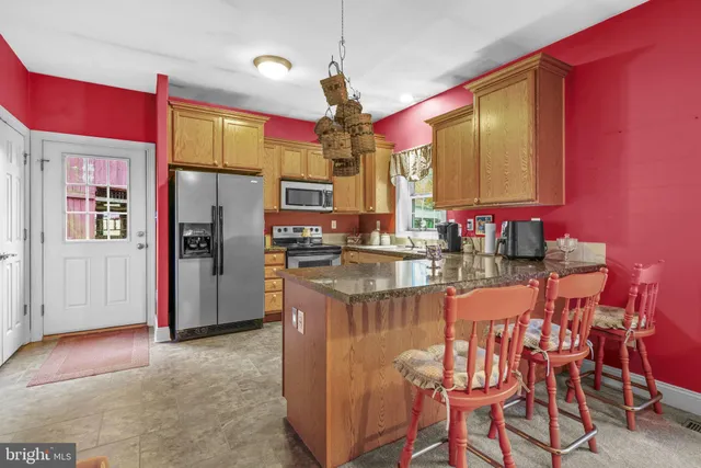 a kitchen with stainless steel appliances granite countertop a kitchen island a stove and a refrigerator
