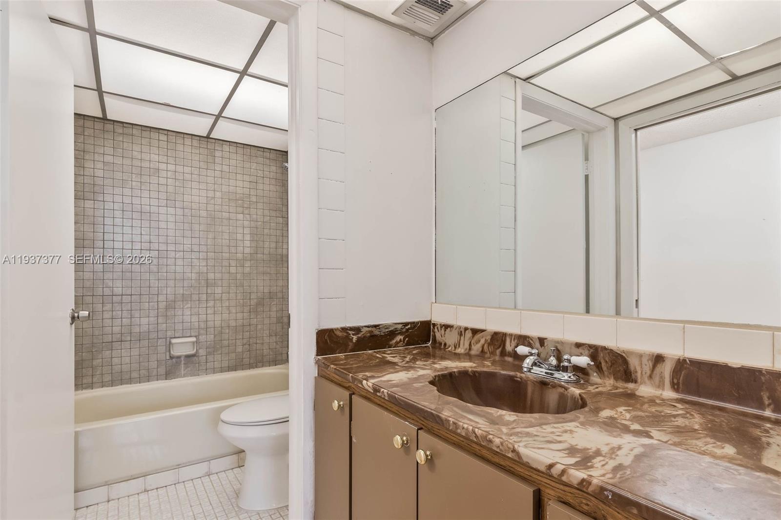 10985 Southwest 107th Street, Unit 310 Miami, FL 33176 - Photo 12 of 30 a bathroom with a granite countertop sink toilet and shower