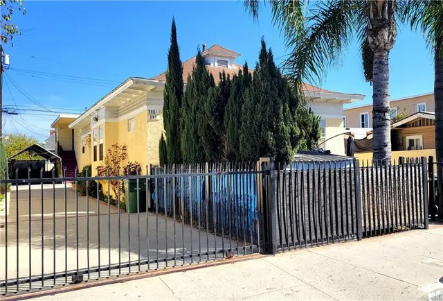 a view of a brick house with a small yard and wooden fence