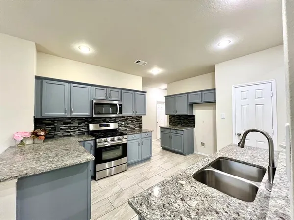 a kitchen with stainless steel appliances granite countertop a sink and stove top oven with wooden floor