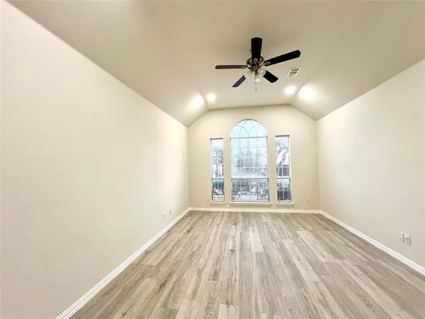 an empty room with wooden floor fan and windows