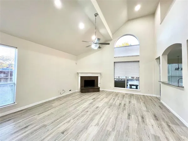 a view of a livingroom with a fireplace a ceiling fan and wooden floor