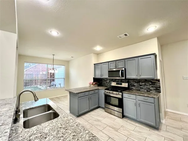 a kitchen with granite countertop a stove a sink and a microwave