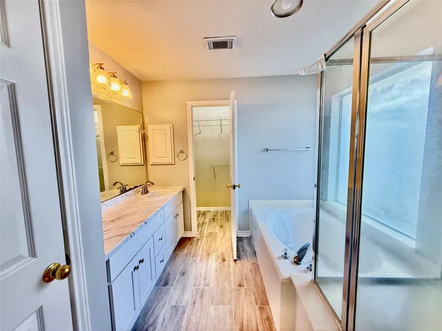 a spacious bathroom with a tub shower and mirror